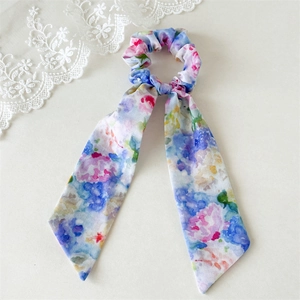 Detailed view of floral chiffon scrunchie with ribbons on white lace background