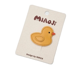Cute yellow leather duck hair clip on display card with detailed stitching and black eyes
