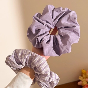 Close-up of oversized purple and checkered fabric scrunchies worn on wrist