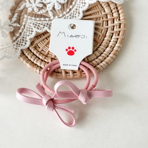 Dettaglio di elastici per capelli rosa con fiocco in nastro su cartoncino bianco