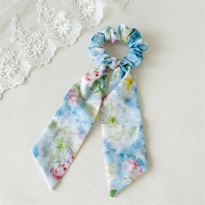 Close-up of floral print ponytail hair tie with long ribbons on light blue fabric