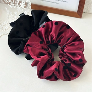 Detail of red and black satin polka dot scrunchies with fashion label and silk texture