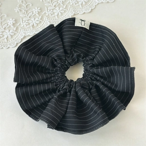 Detail of black and white striped fabric scrunchie with minimalist bow label decoration