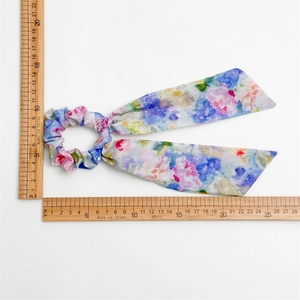 Floral watercolor scrunchie with long ribbons shown against a white background with ruler