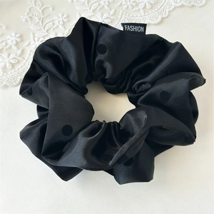 Detail of premium black satin scrunchie with subtle polka dots and Fashion label