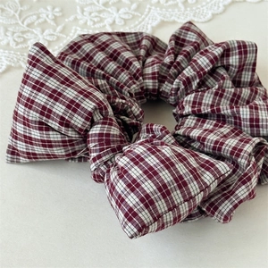 Detailed macro view of a vintage red plaid scrunchie with a matching decorative bow