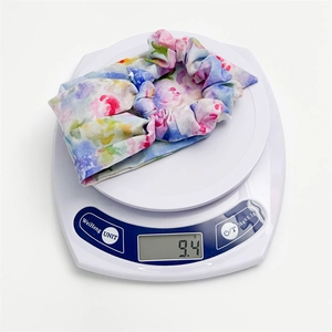 Detail showing colorful floral print scrunchie weighing 9.4g on a digital scale