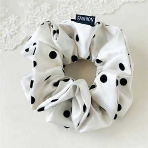 Close-up of white satin scrunchie with black polka dots and Fashion woven label detail