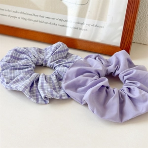 Detail view of purple striped and solid lavender scrunchies set on minimalist desk
