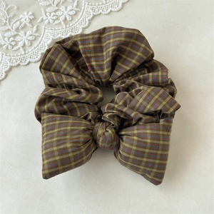 Close-up of a vintage green plaid scrunchie with a fixed bow on a lace background