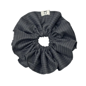 Striped dark gray fabric scrunchie with minimalist white logo tag for stylish hair styling