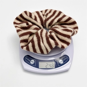 Macro shot of a striped knit hair scrunchie on a scale showing its 24.8g weight