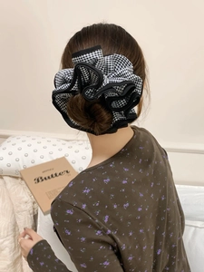 Dettaglio di un elastico per capelli a scacchi bianco e nero con design in tessuto a strati