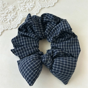 Detail of a vintage plaid bow scrunchie featuring blue and white checkered cotton fabric