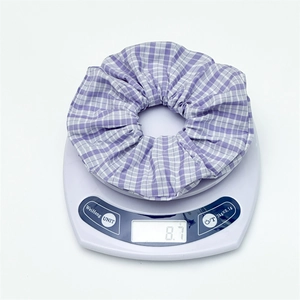 Detail shot showing the lightweight 8.7g purple checkered scrunchie on a digital scale