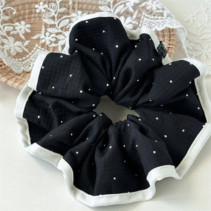 Détail du chouchou noir à pois blancs avec bordure contrastée et tissu à carreaux