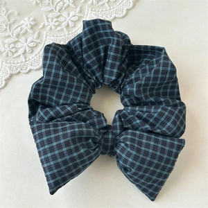 Detail of vintage navy plaid scrunchie with bow decoration on a white lace background