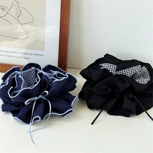 Detailansicht von marineblauen und schwarzen Haargummis mit Karofutter und Schleifenband