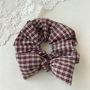 Macro detail of red and white plaid scrunchie with bow decoration on lace background