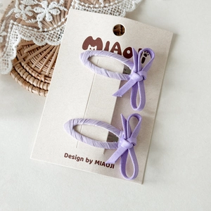 Dettaglio di fermagli per capelli viola con fiocco per bambine su carta da esposizione