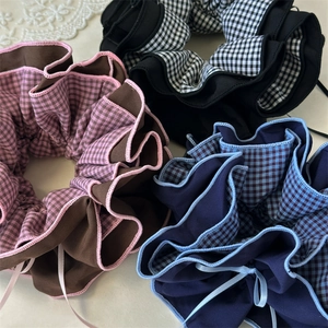 Detail von karierten Haargummis mit Bändern und sauberer Overlock-Stich-Verarbeitung