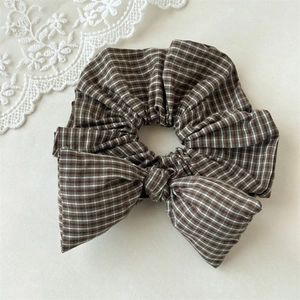 Detail of a brown plaid bow scrunchie with soft cotton texture for hair styling