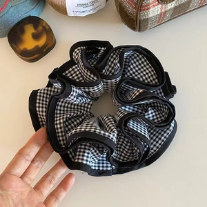 Dettaglio di un elastico per capelli a quadretti bianchi e neri con tessuto multistrato