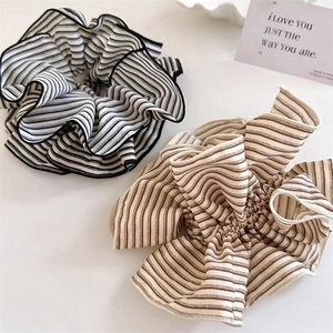 Detail of vintage striped fabric scrunchies in black and brown on a white tray