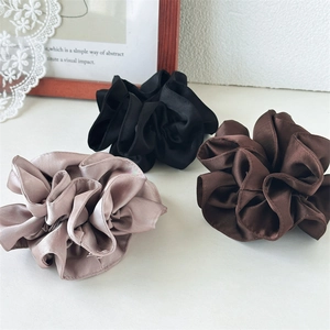 Three oversized satin scrunchies in black, coffee, and beige shown on a white tabletop