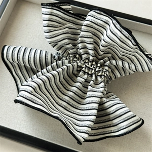 Detailed view of black and white striped scrunchie with pleated texture in a gift box
