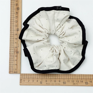 Détail d'un chouchou blanc à carreaux avec strass étincelants et bordure noire