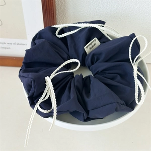 Detailed close-up of blue fabric hair scrunchie with white lace trim and handmade label