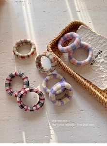 Detail of knitted plaid thick hair scrunchies in various colors on stone background