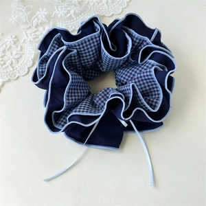 Detailansicht eines Haargummis aus marineblauem Karostoff mit blauen Zierbändern