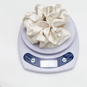 Weight display of white satin scrunchie showing 27.9g on a digital scale for quality