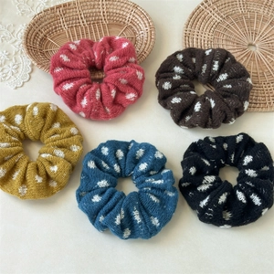 Detailed close-up of colorful knit scrunchies with white polka dots in a woven basket