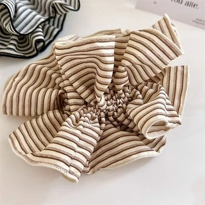 Close-up detail of oversized striped scrunchie with pleated texture and soft fabric finish