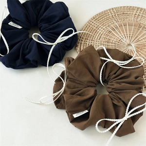 Close-up of blue and brown scrunchies with white lace bows and fabric labels