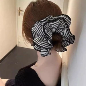 Macro detail of oversized black and white striped fabric scrunchie on a ponytail