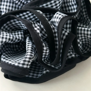 Dettaglio del tessuto vichy a quadretti bianchi e neri con bordi neri sull'elastico scrunchie