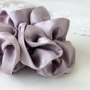 Detailed close-up of smooth lavender satin fabric texture and stitching of the scrunchie