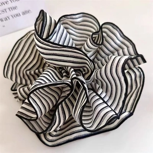 Close-up of black and white striped scrunchie with ruffled edges on a white background