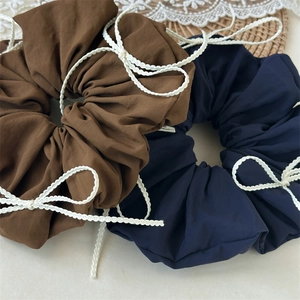 Detailed texture of blue and brown fabric hair scrunchies with white lace bow accents