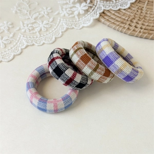 Detail of four colorful checkered fabric hair ties with soft knit texture on lace