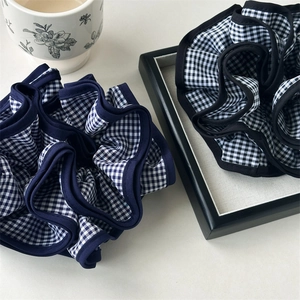 Dettaglio di elastici scrunchie a scacchi neri e blu con trama in tessuto plissettato