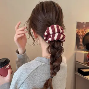 Détail d'un chouchou en tricot rayé rouge et blanc sur une coiffure tressée