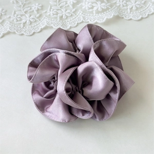 Detail shot of dusty purple satin scrunchie with pleated texture and silky metallic sheen