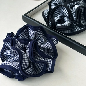 Dettaglio dell'elastico scrunchie a quadretti blu e bianchi con trama a strati