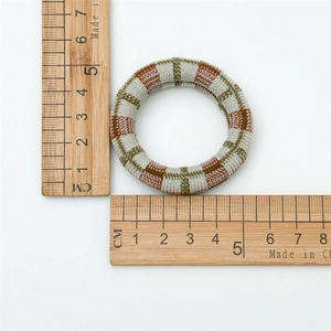 Close-up of woven plaid hair tie on white background with wooden ruler measuring 5cm size