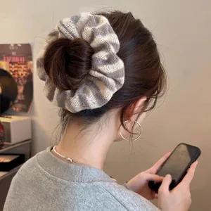 Gros plan d'un chouchou en tricot épais à rayures gris et blanc porté en chignon